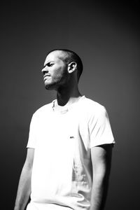 Young man looking away against black background