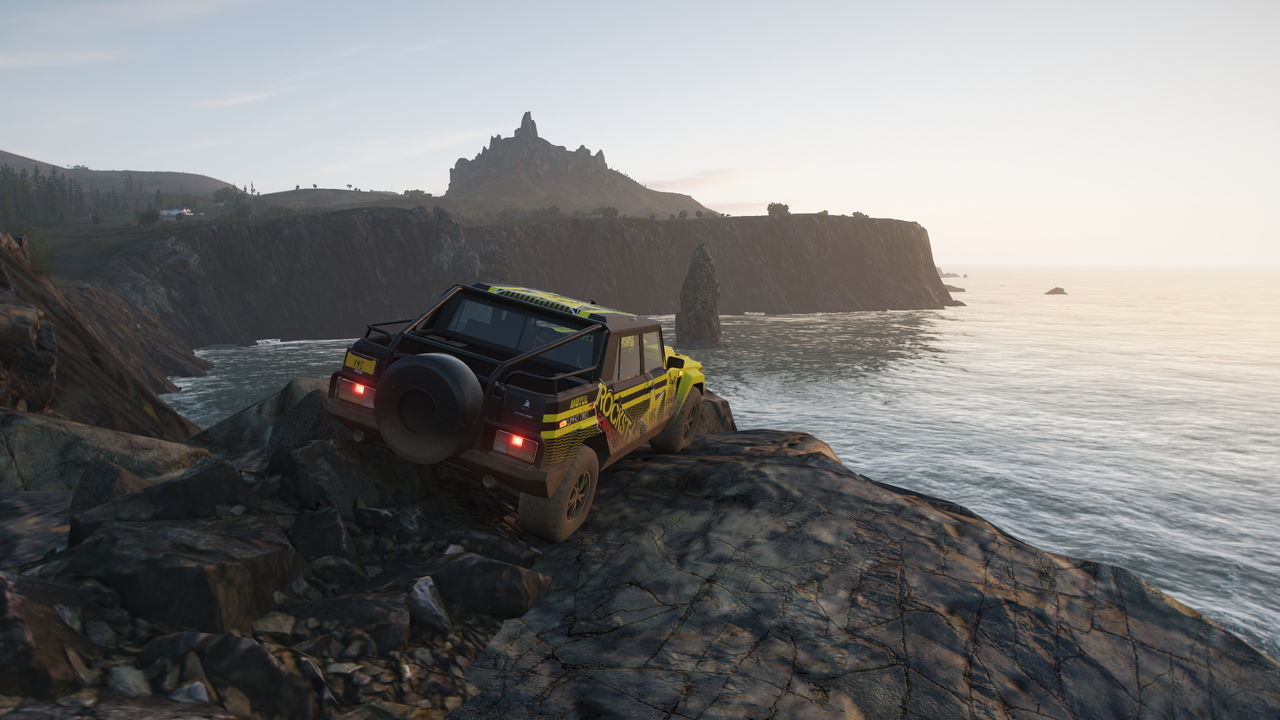 CAR ON ROCK FORMATION ON BEACH AGAINST SKY