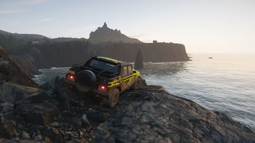 Car on rock by sea against clear sky