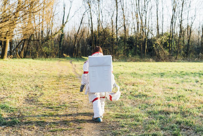 Young female explorer walking on forest path during sunny day