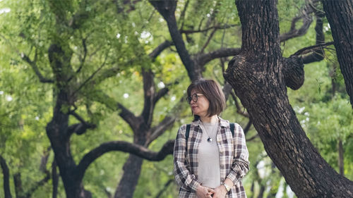 Side view of woman standing against trees