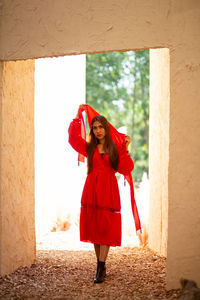 Full length of a woman standing against red wall