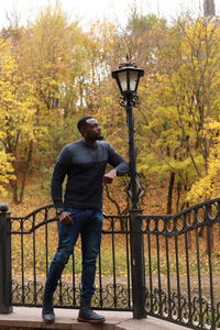 Full length of man standing by railing during autumn