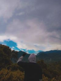 Rear view of man standing on mountain against sky