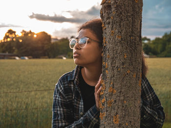 Portrait of boy looking away against tree trunk