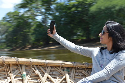 Young woman taking selfie while sitting in boat