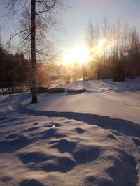 Snow covered field against sky during sunset