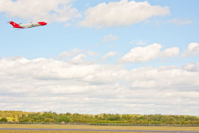 Low angle view of airplane flying over field against sky