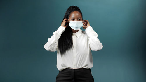 Young woman wearing mask against blue background