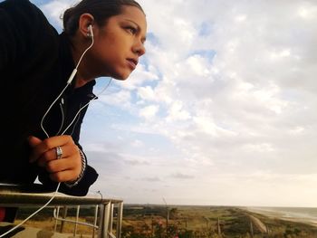 Young woman using mobile phone against sky