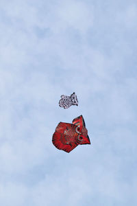 Low angle view of red bird flying against sky