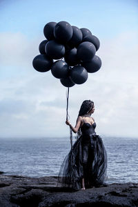 Full length of woman on rock in sea against sky