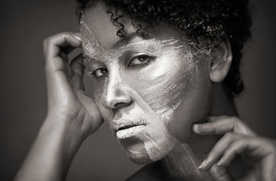 Close-up portrait of woman with face paint against gray background