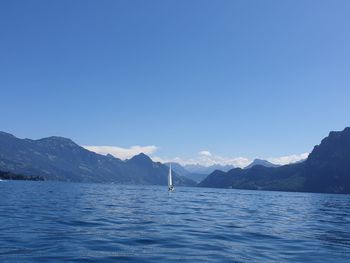 Scenic view of sea and mountains against clear blue sky