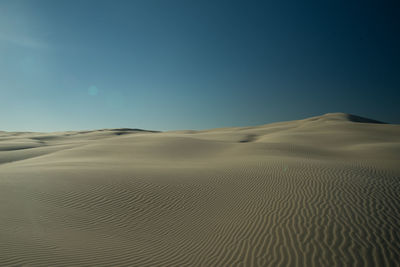 Scenic view of desert against clear blue sky