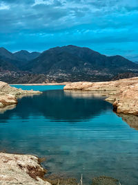 Scenic view of lake by mountains against sky