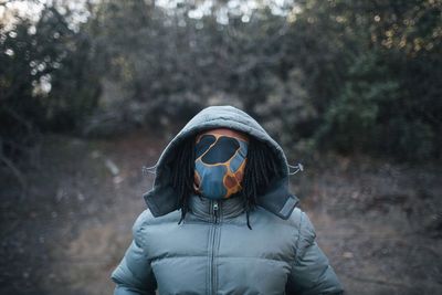 Man covering face with fabric while standing at forest