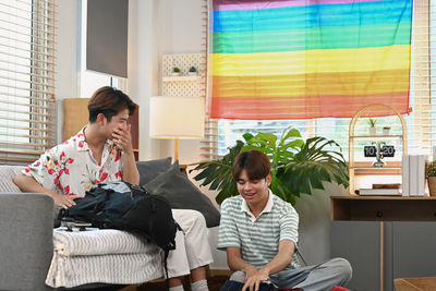 Friends using digital tablet while sitting on sofa at home