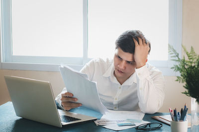 Young man using mobile phone while sitting on table