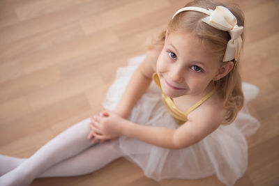 Portrait of ballet dancer sitting on wooden floor