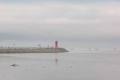 Lighthouse by sea against sky