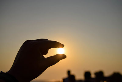 Silhouette person holding sun during sunset