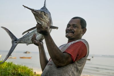 Man holding big fish against clear sky