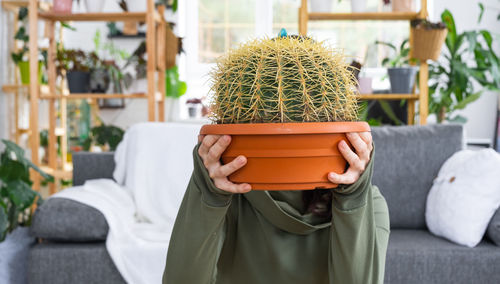 Rear view of woman holding potted plant