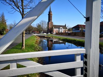 Reflection of building in lake against clear blue sky