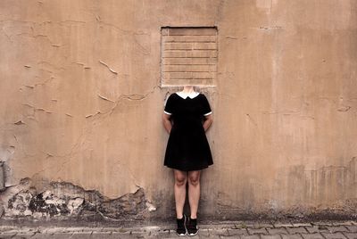 Digital composite image of decapitated woman standing against wall