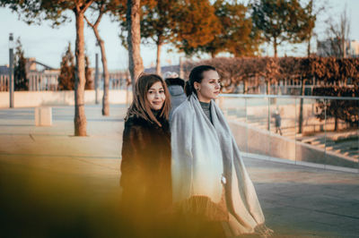 Portrait of smiling young woman standing against trees