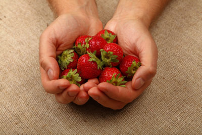Cropped hands holding strawberries on table