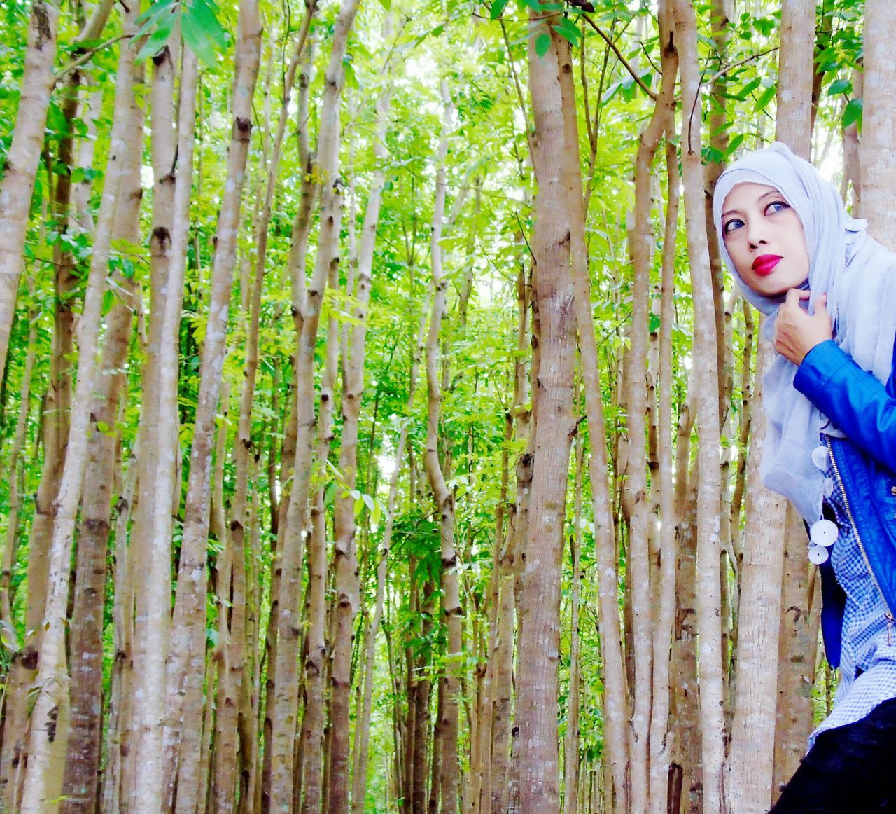 WOMAN STANDING ON TREE TRUNK IN FOREST