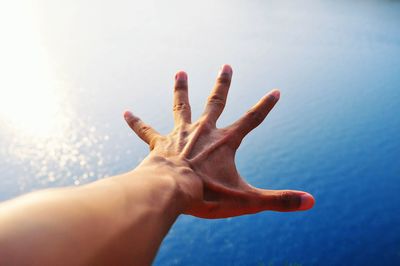 Close-up of person gesturing against lake