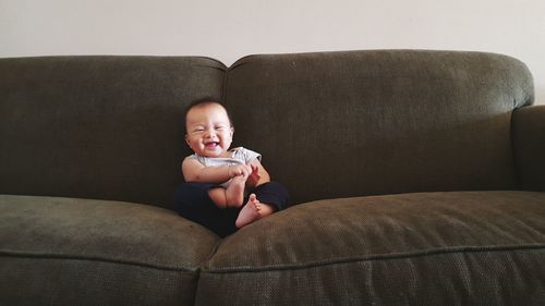 Smiling cute boy sitting on sofa at home