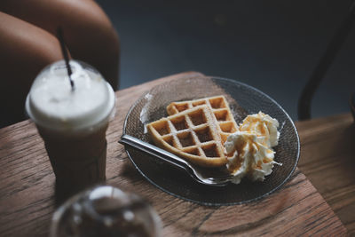 Close-up of hand holding ice cream on table