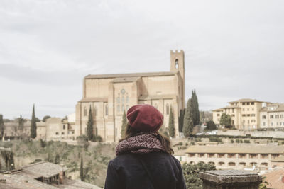 Rear view of woman looking at cityscape against sky