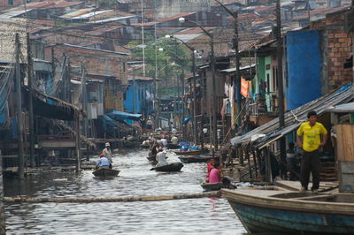 People on boats in canal along city