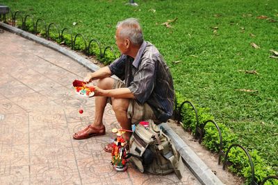 Senior man selling toys while sitting in park
