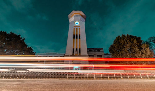 Light trails on tower against sky at night