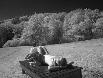 Woman resting on field by tree