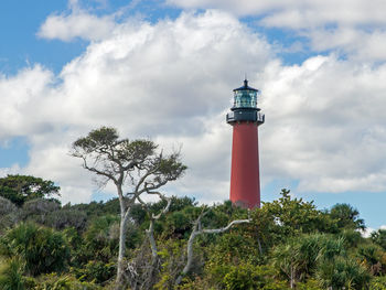 Lighthouse by trees against sky