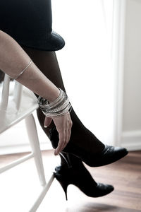 Low section of woman wearing high heels and stockings at home