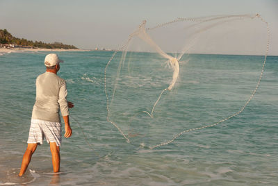 Full length of a fisherman on the beach with a fishing net