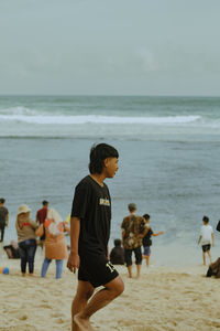 Rear view of woman standing at beach against sky