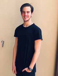 Portrait of young man standing against wall