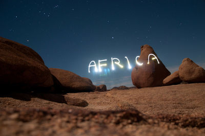 Rocks on beach against sky at night