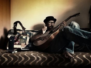 Man sitting on guitar at home