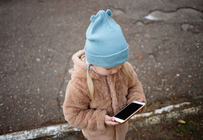 Rear view of girl using mobile phone in winter