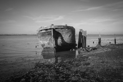 Old boat at sea shore against sky